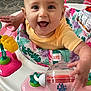 baby, child, smiling, face, eyes, hands, toy, walker, activity_center, colorful, yellow_shirt, happy, indoor, floor, plastic_toy, play, infant, cute, joyful, person