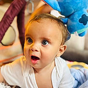 Ghael a rejoint le concours — aidez-le/la à gagner de superbes lots ! baby, baby_toys, blanket, blue_eyes, child, closeup, crawling, cute, head, homedecor, indoor, infant, mouth_open, person, portrait, skin, soft_toys, surprised_expression, white_clothing, young_child