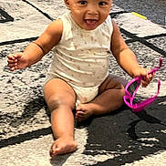 Aniyah is registered to the contest to win money with this photo: baby, child, infant, sitting, carpet, floor, pink_sunglasses, toy, happy, smiling, playful, indoor, cute, face, arms, legs, onesie, earrings, tongue, person