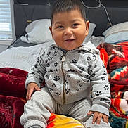 Daniel is registered to the contest to win money with this photo: child, toddler, smile, sitting, hoodie, paw_prints, blanket, bed, pillow, indoors, happy, cozy, clothing, face, person, home, cute, warm, casual, portrait
