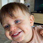 Adam a rejoint le concours — aidez-le/la à gagner de superbes lots ! child, toddler, smiling, blue_eyes, baby_teeth, dimples, close_up, face, hand, hair, shirt, highchair, indoor, living_room, television, wooden_cabinet, skin, candid, happiness, portrait