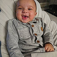 Logann a rejoint le concours — aidez-le/la à gagner de superbes lots ! baby, smiling, infant, sweater, buttons, cozy, indoor, cushion, seat, happy, child, portrait, young, cute, clothing, hand, face, person, relaxed, warm