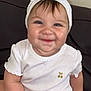 baby, child, smile, headband, bow, white_clothing, pacifier, sitting, couch, indoor, cute, chubby, happy, face, person, infant, skin, young_child, portrait, small_hand