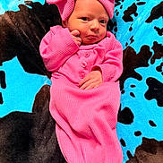 Mylee is registered to the contest to win money with this photo: baby, infant, pink_clothing, headband, blanket, blue, black, pattern, cute, newborn, portrait, posing, soft_texture, sleepwear, small_hands, lying_down, child, warm, indoors, cozy