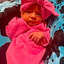 baby, infant, pink_clothing, headwear, bow, blanket, blue, black, pattern, newborn, cute, portrait, lying_down, small_hands, indoors, soft_texture, warm, cozy, child, face