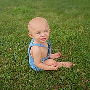 Colt joined the competition — help win amazing prizes! child, toddler, grass, outdoor, barefoot, blue_eyes, romper, greenery, sitting, person, lawn, nature, summer, cute, smiling, baby, skin, head, playful, daylight