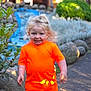 Neo is registered to the contest to win money with this photo: child, toddler, orange_clothing, blonde_hair, outdoor, garden, rocks, pathway, smiling, happy, face, person, sunlight, greenery, plants, daylight, nature, casual_clothing, walking, cute
