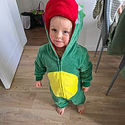 Neo joined the competition — help win amazing prizes! toddler, child, costume, dinosaur, hood, red, green, yellow, onesie, barefoot, indoor, wooden_floor, curious, standing, person, clothing, cute, face, expression, home