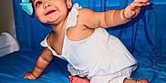 Rebecca is registered to the contest to win money with this photo: baby, child, girl, bow, white_dress, blue_bedspread, blue_curtains, crawling, smiling, happy, indoor, bed, foot, hand, face, portrait, infant, cute, person, skin