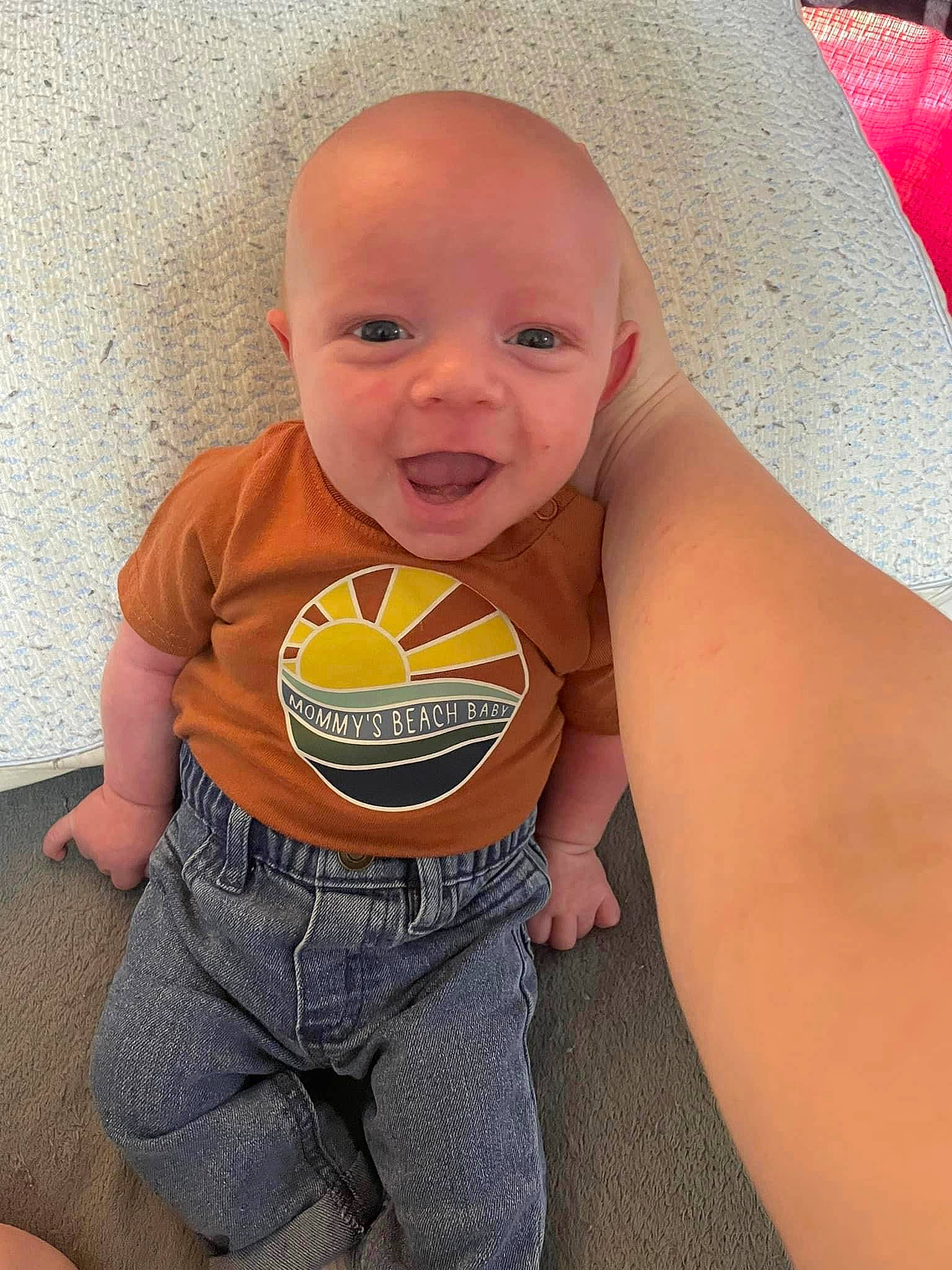 Parker is registered to the contest to win money with this photo: arm, baby_toddler_clothing, cheek, eye, finger, happy, human_body, joint, leg, mouth, neck, nose, orange, person, skin, sleeve, smile, stomach, textile, thigh