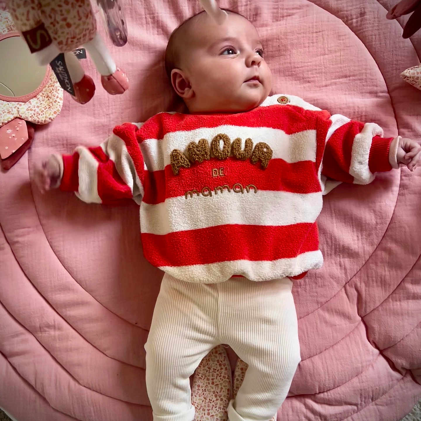 Elena participe au concours pour gagner de l'argent avec cette photo : baby, infant, child, red_sweater, striped_clothing, white_pants, pink_quilt, soft_toys, lying_down, indoor, cute, cozy, toddler, sleeping_mat, plush_toys, warm_colors, candid, portrait, gazing, comfortable