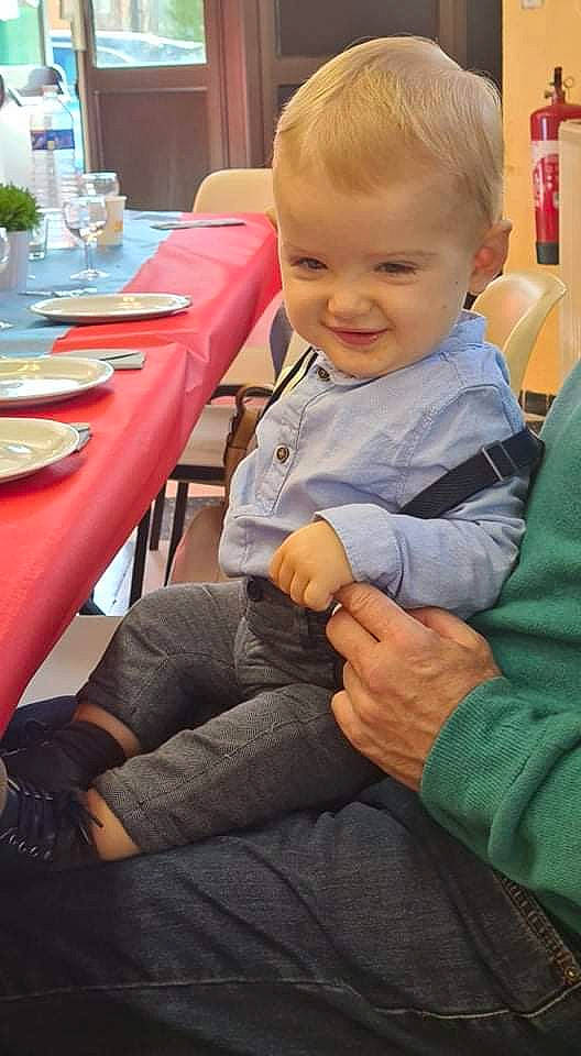 Elio a rejoint le concours — aidez-le/la à gagner de superbes lots ! baby, baby_toddler_clothing, chair, child, dishware, finger, flooring, fun, joy, lap, person, plate, sitting, skin, smile, table, tablecloth, tableware, thumb, toddler