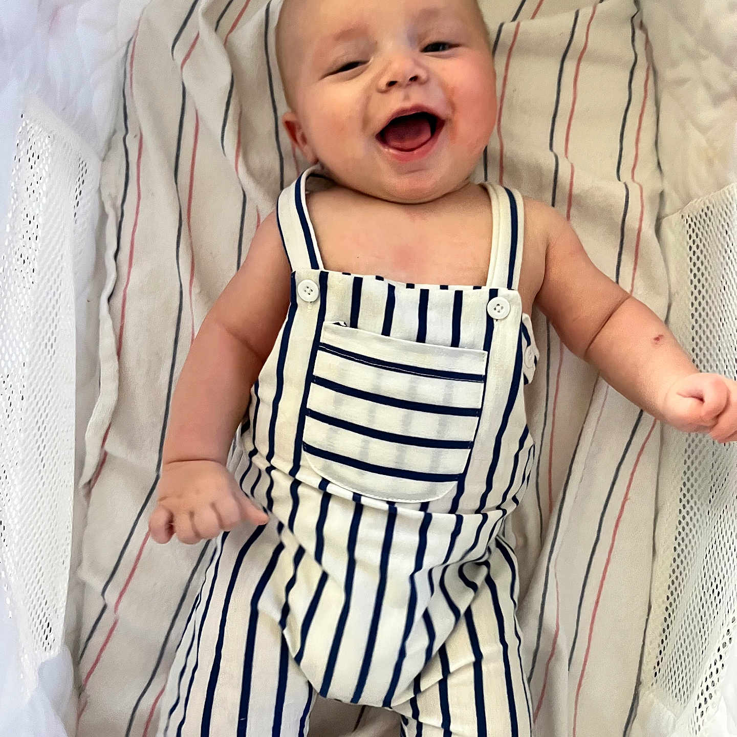 Kyzir Kaid is registered to the contest to win money with this photo: arm, baby, blanket, child, crib, cute, fabric, face, hand, happy, infant, lying_down, mesh, pattern, playful, portrait, romper, skin, smiling, striped_clothing