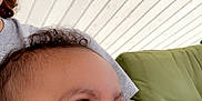 Kyngstun is registered to the contest to win money with this photo: baby, smile, face, child, happy, curly_hair, person, indoor, couch, green_cushion, skin, closeup, portrait, infant, cheerful, young_child, room, furniture, head, looking_away