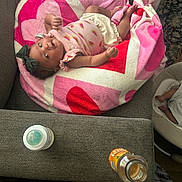 Xolani is registered to the contest to win money with this photo: baby, infant, blanket, heart_pattern, couch, bottle, juice_bottle, bow, pink_clothing, watermelon_print, baby_swing, feet, shoes, indoor, furniture, cute, child, person, relaxing, home