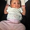 baby, infant, child, car_seat, clothing, pink_pants, white_top, floral_pattern, face, hands, eyes, skin, hair, seat, safety_warning, indoors, cute, portrait, young, laying