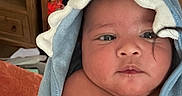 Hugo Lee is registered to the contest to win money with this photo: baby, blanket, blue_towel, child, clothing, curly_hair, cute, expression, face, frilled_edge, indoors, infant, newborn, person, portrait, shelf, skin, soft_light, towel, wrapped