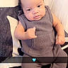 baby, infant, child, knitted_outfit, grey_clothing, socks, bed, pillow, pattern, heart_emoji, gesture, curious_expression, indoor, portrait, cute, cozy, young_child, person, seated, blanket