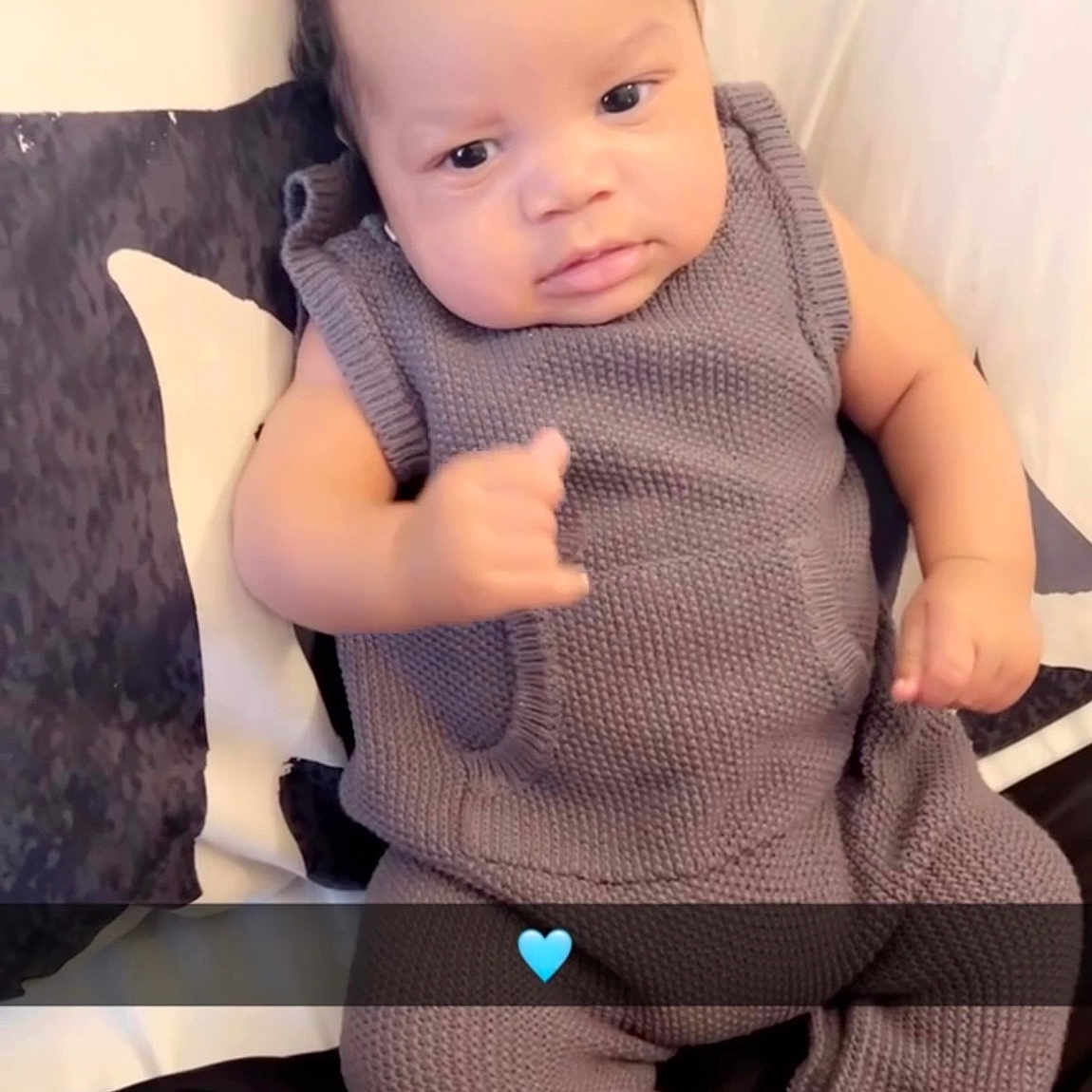 Jyaair joined the competition — help win amazing prizes! baby, infant, child, knitted_outfit, grey_clothing, socks, bed, pillow, pattern, heart_emoji, gesture, curious_expression, indoor, portrait, cute, cozy, young_child, person, seated, blanket