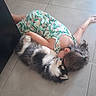 child, dog, floor, tile, hugging, floral_dress, cute, pet, animal, snuggling, cozy, indoor, affection, laying_down, black_and_white, fur, hair, young, together, bond