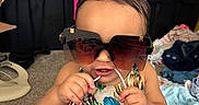 Asiya joined the competition — help win amazing prizes! toddler, child, sunglasses, clothing, indoor, carpet, playful, cute, baby, person, fashion, accessories, messy_room, seat, colorful, summer_wear, portrait, fun, young_child, casual