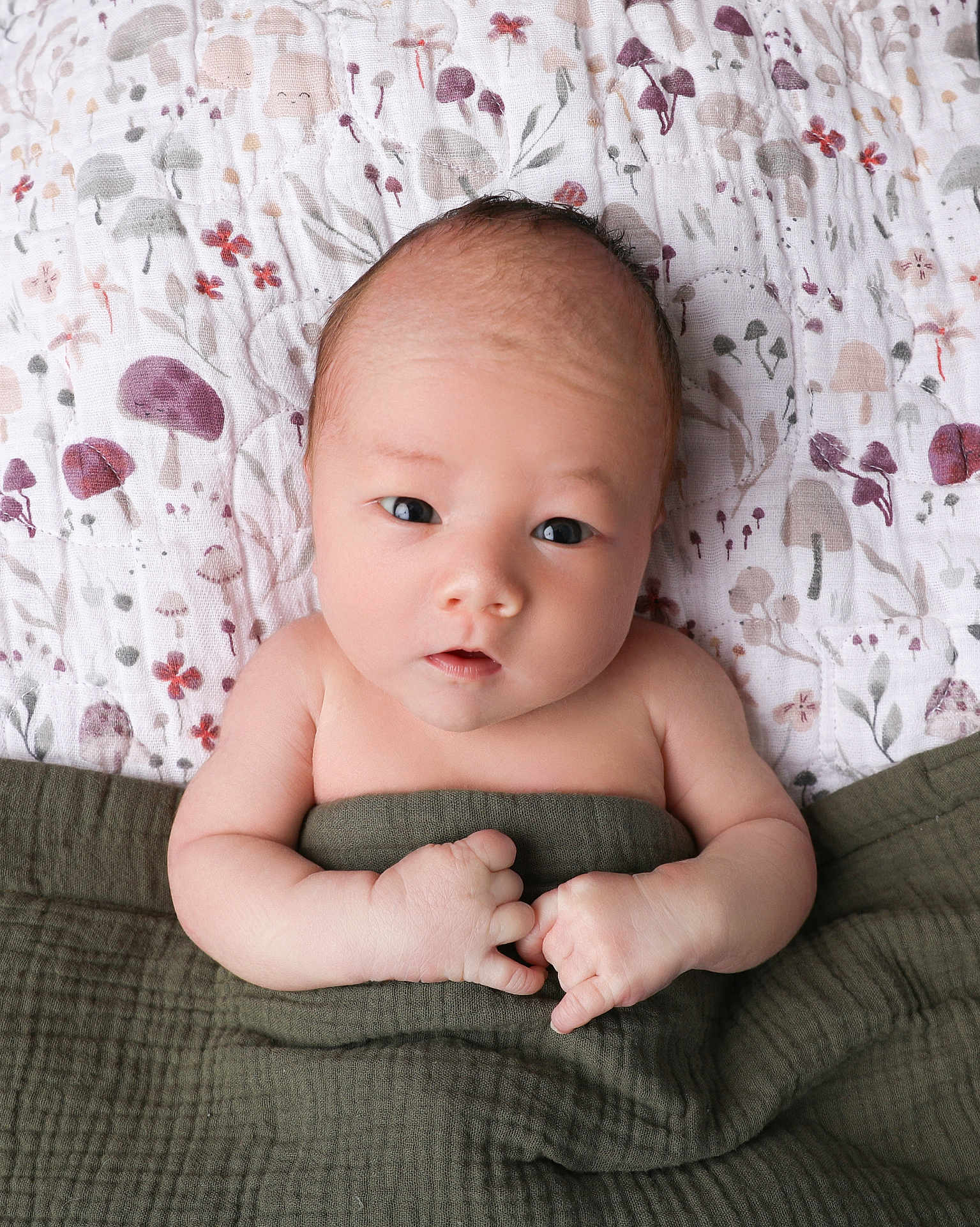 Milo joined the competition — help win amazing prizes! baby, infant, blanket, quilt, mushroom_pattern, flower_pattern, skin, face, hands, cute, newborn, lying_down, soft_texture, indoors, child, portrait, sleepwear, curious_expression, small_hands, wrapped