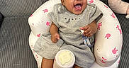 Sanaa is registered to the contest to win money with this photo: baby, infant, smiling, laughing, bow, gray_dress, inflatable_chair, pink_bunnies, sitting, sock, cute, happy, indoor, couch, child, person, comfort, playful, baby_accessories, home