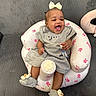 baby, infant, smiling, laughing, bow, gray_dress, inflatable_chair, pink_bunnies, sitting, sock, cute, happy, indoor, couch, child, person, comfort, playful, baby_accessories, home