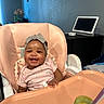 Sanaa is registered to the contest to win money with this photo: baby, high_chair, smile, headband, baby_food, spoon, indoor, tablet, flower, plant, furniture, person, child, happy, peach, clothing, table, face, infant, home