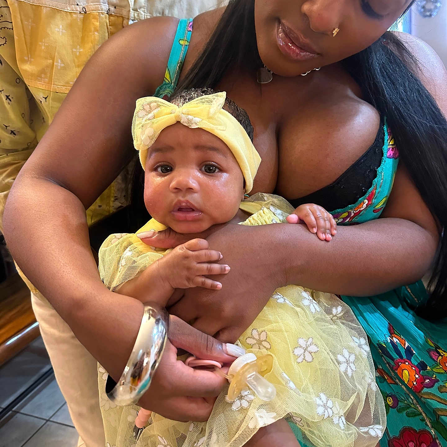 Sanaa joined the competition — help win amazing prizes! baby, woman, child, yellow_dress, headband, holding, indoor, portrait, family, love, affection, colorful_clothing, bracelet, closeup, skin, face, eyes, hand, floor, person