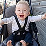 baby, car, child, clothing, daylight, expression, feet, hands, happy, infant, joy, metal_shutter, outdoor, person, portrait, seatbelt, sidewalk, smiling, stroller, urban