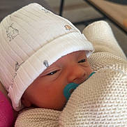 Ayden participe au concours pour gagner de l'argent avec cette photo : baby, newborn, pacifier, beanie_hat, knit_sweater, blanket, close_up, infant, portrait, sleepy, face, hand, indoor, sofa, coffee_table, calm, soft_texture, pink_clothing, hat_pattern, comforting