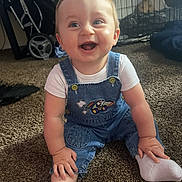 Mavrick joined the competition — help win amazing prizes! baby, child, smiling, denim_overalls, white_shirt, socks, carpet, indoor, stroller, pet_crate, happy, sitting, cute, infant, portrait, person, young_child, playful, floor, casual_clothing