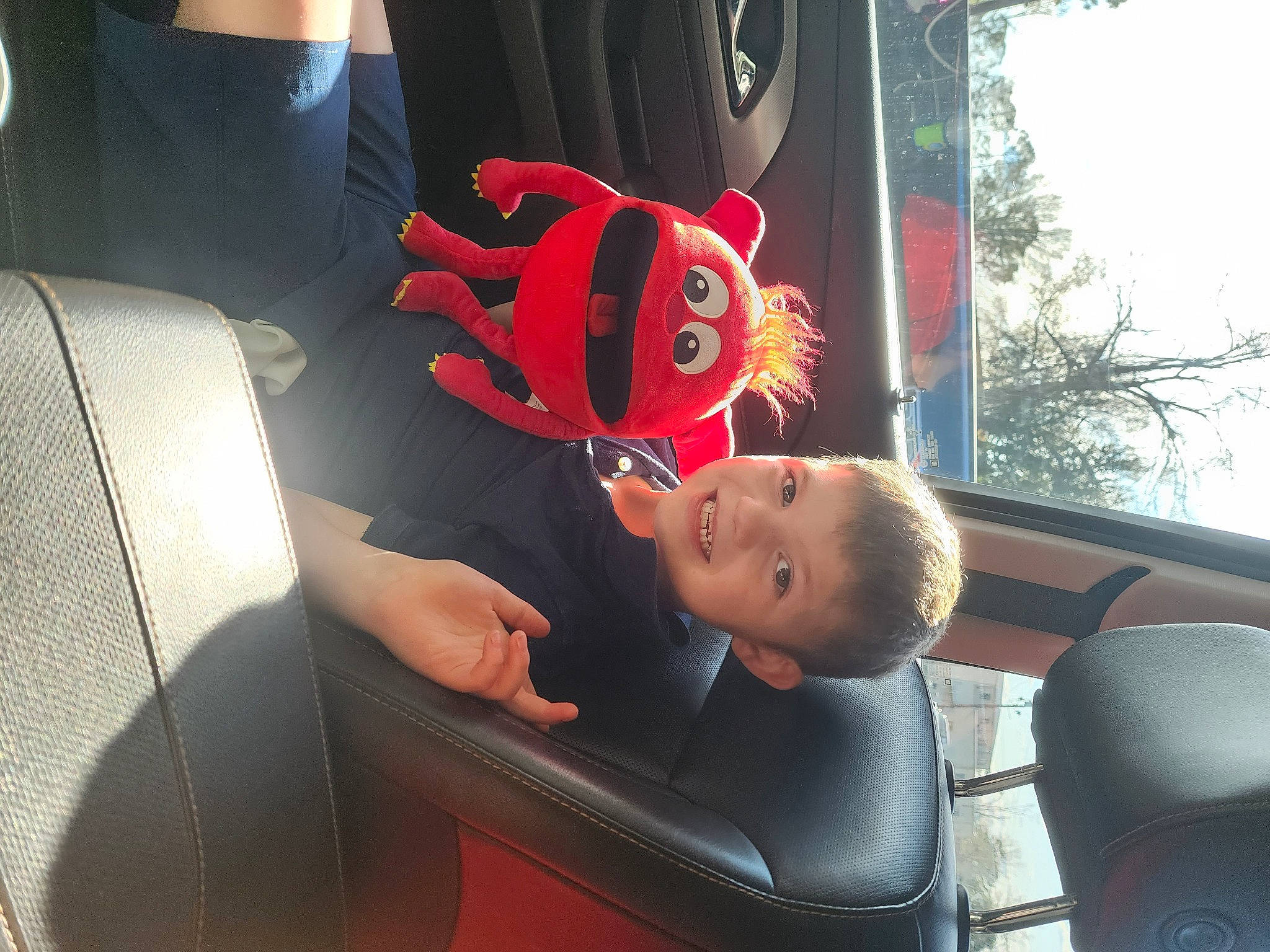 Taran is registered to the contest to win money with this photo: auto_part, automotive_design, automotive_exterior, car_seat, car_seat_cover, carmine, comfort, family_car, fictional_character, fun, joy, luxury_vehicle, motor_vehicle, person, personal_luxury_car, personal_protective_equipment, steering_wheel, toddler, tree, vehicle