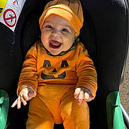 Mily-Rose participe au concours pour gagner de l'argent avec cette photo : baby, pumpkin_costume, car_seat, orange, smiling, happy, child, infant, costume, cute, holiday, jack_o_lantern, seat, clothing, indoors, person, headwear, celebration, portrait, seatbelt