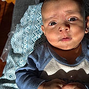 Nirvikh joined the competition — help win amazing prizes! baby, infant, face, hands, blanket, pattern, clothing, blue, skin, closeup, light, shadow, expression, curious, indoors, person, child, portrait, newborn, texture