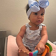 Gianna Ramirez joined the competition — help win amazing prizes! baby, child, headband, bow, toy, pink, dress, shoes, indoor, sitting, curious, infant, cute, play, person, footwear, hand, face, skin, young