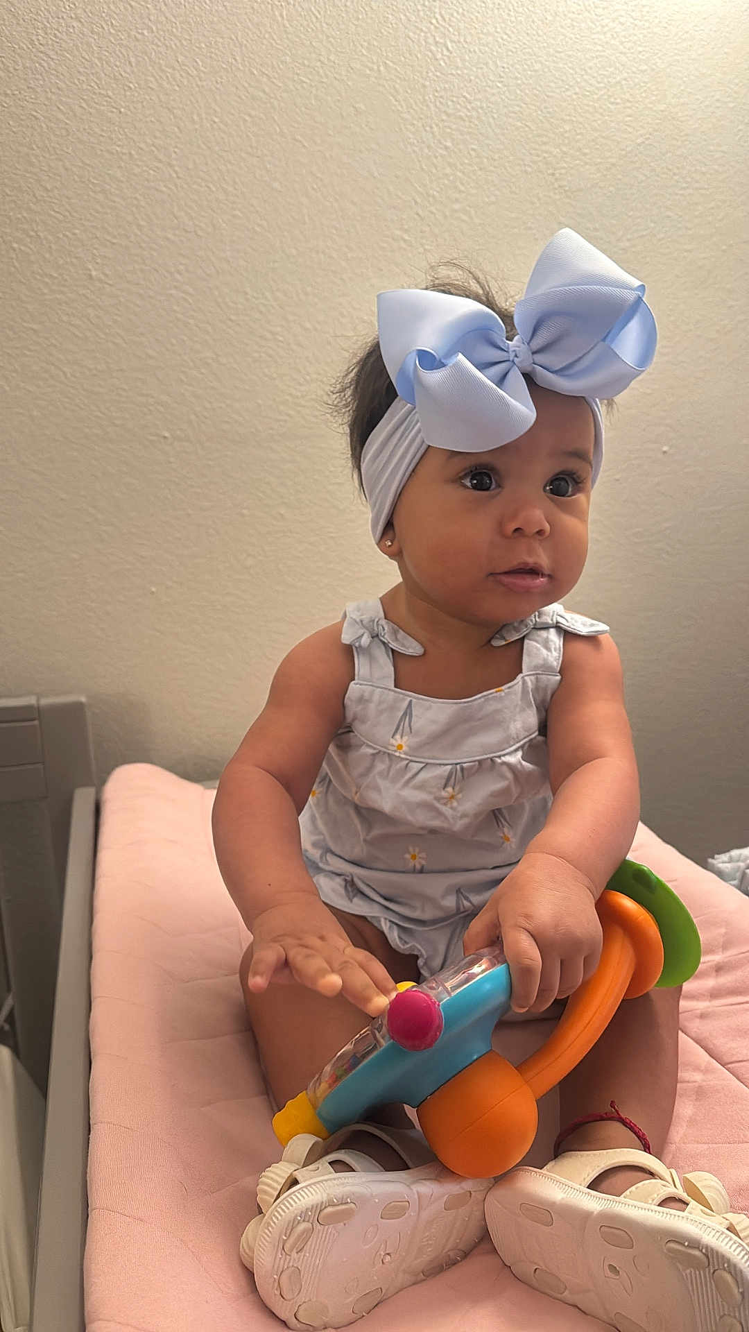Gianna Ramirez joined the competition — help win amazing prizes! baby, child, headband, bow, toy, pink, dress, shoes, indoor, sitting, curious, infant, cute, play, person, footwear, hand, face, skin, young