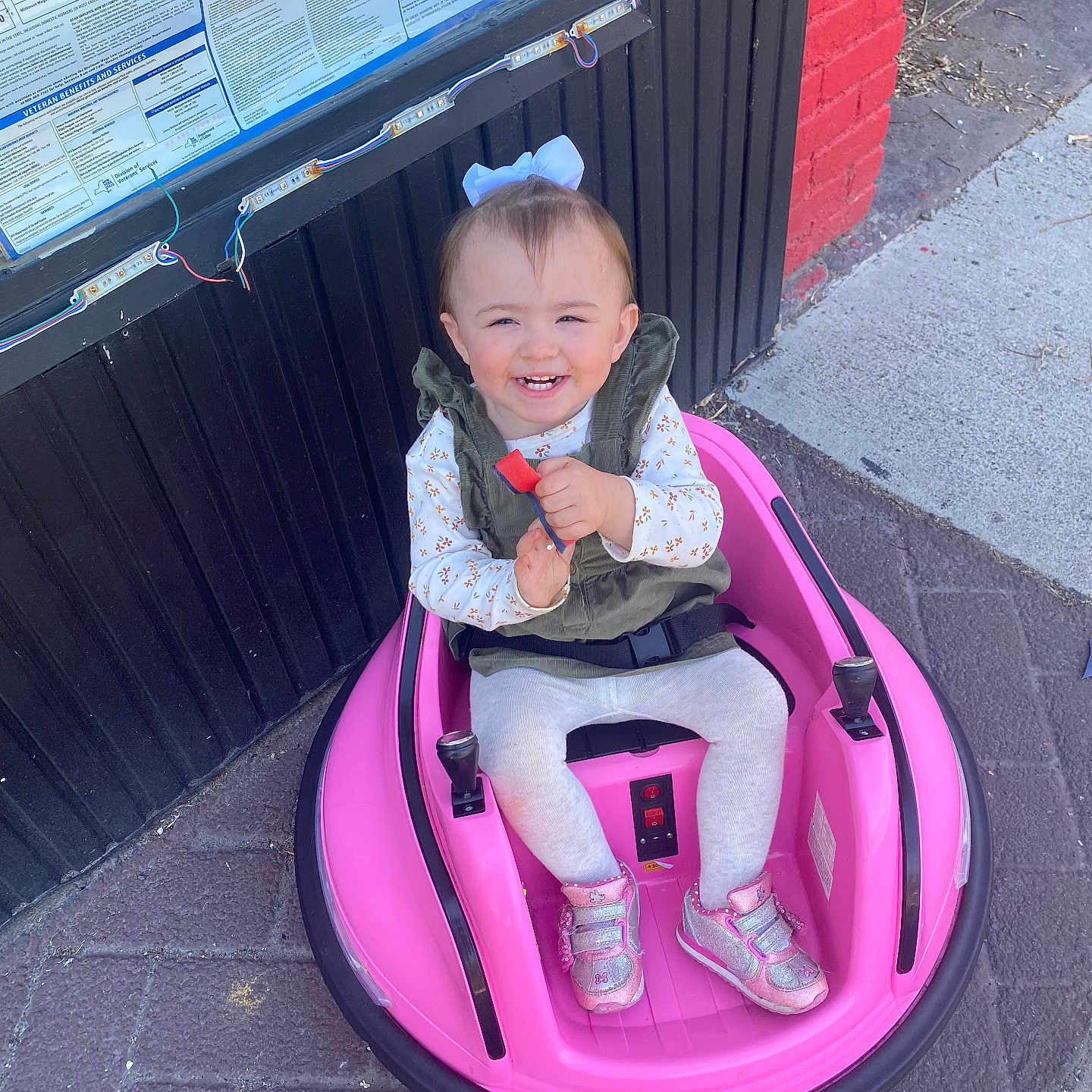 Lilyanna joined the competition — help win amazing prizes! architecture, baby, building, city, clothing, coat, face, footwear, head, jacket, outdoors, person, photography, portrait, road, shelter, shoe, sitting, street, urban