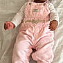 baby, child, infant, smiling, curly_hair, overalls, pink_clothing, white_shirt, lying_down, blanket, soft_texture, cute, portrait, indoors, comfortable, happy, young_child, skin, face, feet