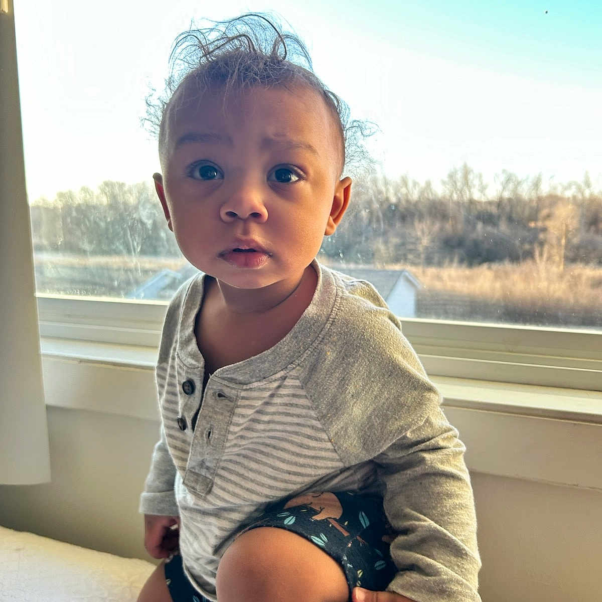 Vasilios Babis joined the competition — help win amazing prizes! background, bed, child, clothing, curious, daylight, expression, face, hair, hand, indoor, long_sleeves, natural_light, patterned_shorts, person, sitting, skin, toddler, window, young_child