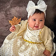Keila is registered to the contest to win money with this photo: baby, bow, cardigan, child, clothing, cute, dress, face, hand, happy, headband, indoor, infant, leaf, person, polka_dots, portrait, sitting, smiling, warm