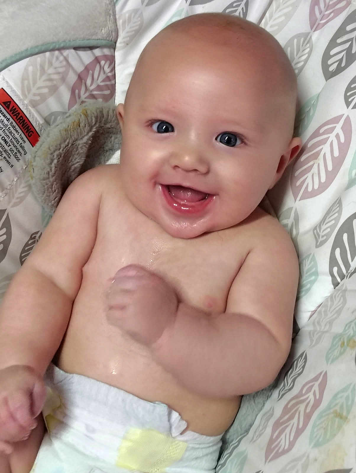 Maximus is registered to the contest to win money with this photo: baby, smiling, infant, diaper, cute, face, child, happy, skin, arm, hand, seat, cushion, pattern, fabric, blue_eyes, bare_chest, portrait, indoors, comfort