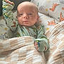 Ryker joined the competition — help win amazing prizes! baby, infant, blanket, pajamas, dinosaur_print, cushion, face, hand, bedroom, comfort, cute, child, sleepwear, raising_arm, soft_light, indoor, portrait, smile, resting, young_child