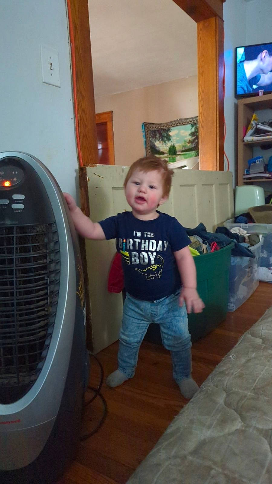 Daylen is registered to the contest to win money with this photo: audio_equipment, baby_toddler_clothing, bookcase, child, circle, flooring, fun, gas, hardwood, home_appliance, machine, major_appliance, mechanical_fan, person, product, shelf, shelving, standing, t_shirt, toddler