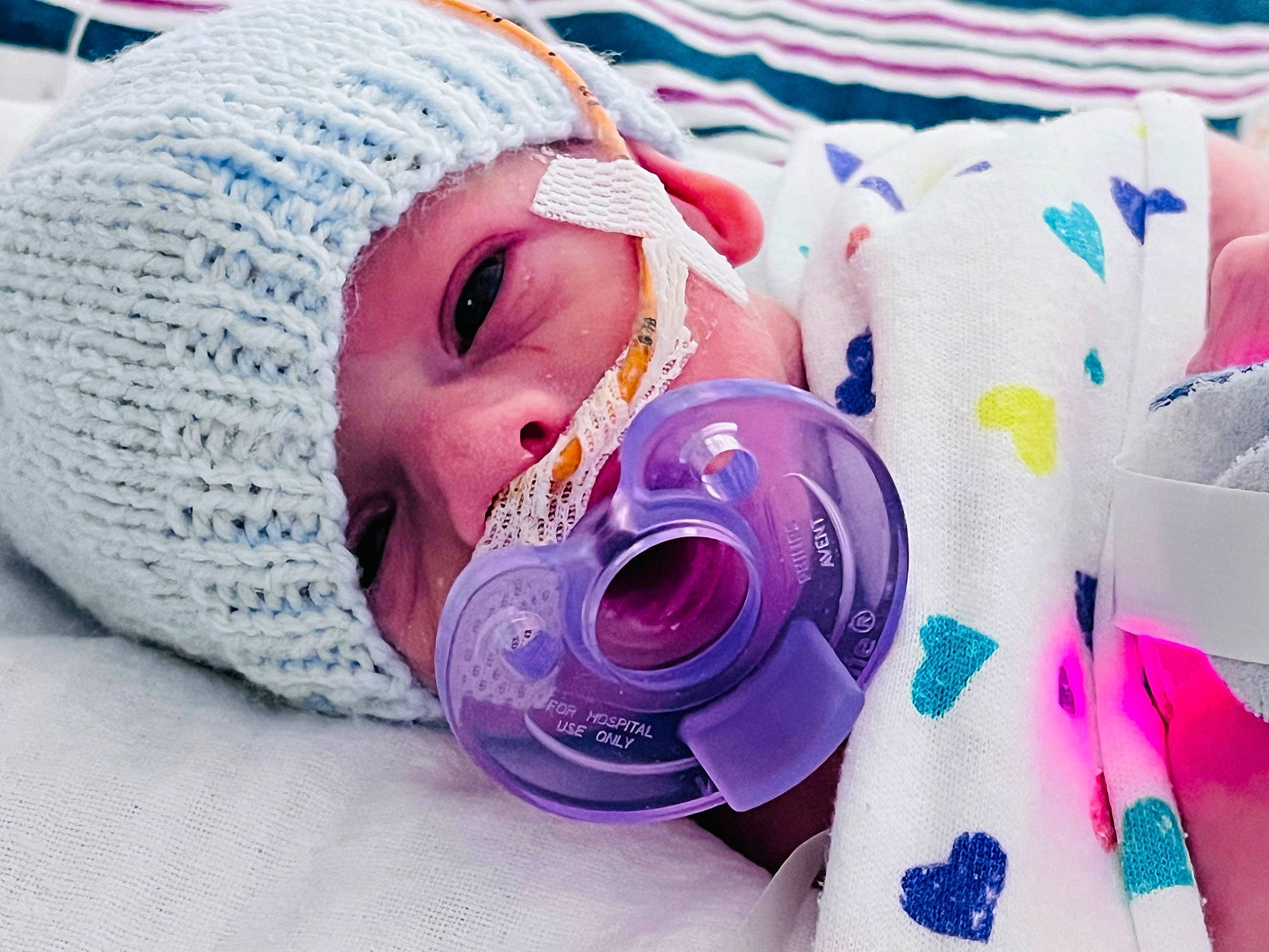 Eli is registered to the contest to win money with this photo: baby, cap, child, drinkware, electric_blue, eyelash, fashion_accessory, happy, headgear, headwear, knit_cap, linens, magenta, pattern, person, pink, purple, skin, smile, textile