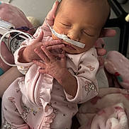 Treazure is registered to the contest to win money with this photo: newborn, baby, infant, hospital, medical_tube, pink_onesie, blanket, sleeping, cute, hand, face, person, child, healthcare, tenderness, cradled, soft, delicate, resting, indoors