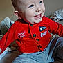 Ransom joined the competition — help win amazing prizes! baby, child, smiling, red_jacket, blue_eyes, sitting, indoor, blanket, bed, happy, cute, portrait, clothing, infant, face, person, young_child, casual, cozy, playful