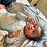 Wynterr is registered to the contest to win money with this photo: baby, child, infant, onesie, owl_print, gummy_worm, candy, blanket, cushion, indoor, curly_hair, person, lying_down, soft_texture, radiator, wall, floor, hand, face, expression