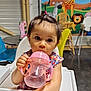 Juliana a rejoint le concours — aidez-le/la à gagner de superbes lots ! toddler, child, high_chair, sippy_cup, pink, water, face, hair, pony_tail, animal_mural, giraffe, zebra, lion, indoor, table, chair, colorful, playful, cute, baby